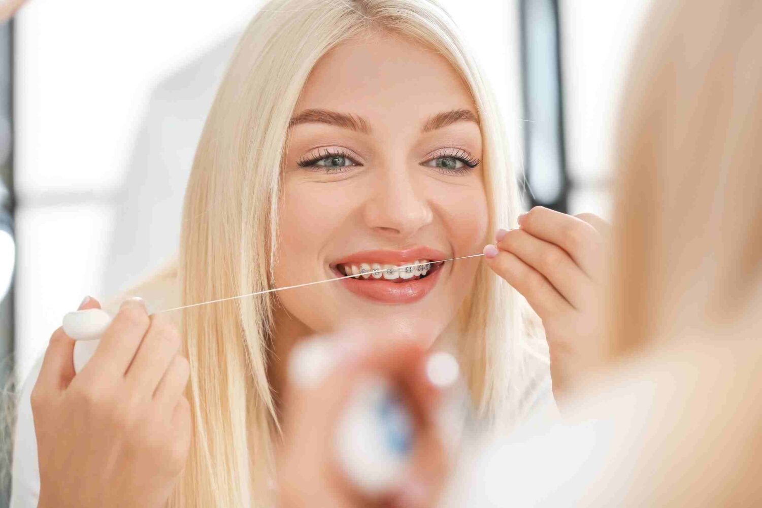 Woman flossing teeth in mirror