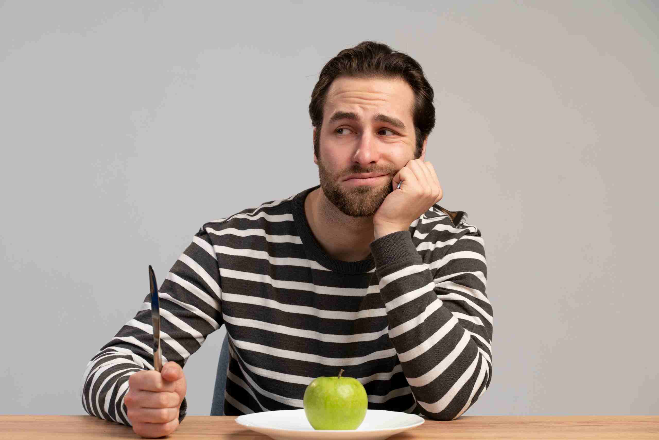 Man eating apple and looking sad