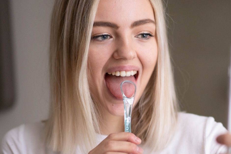 woman scraping tongue with bluem tongue scraper