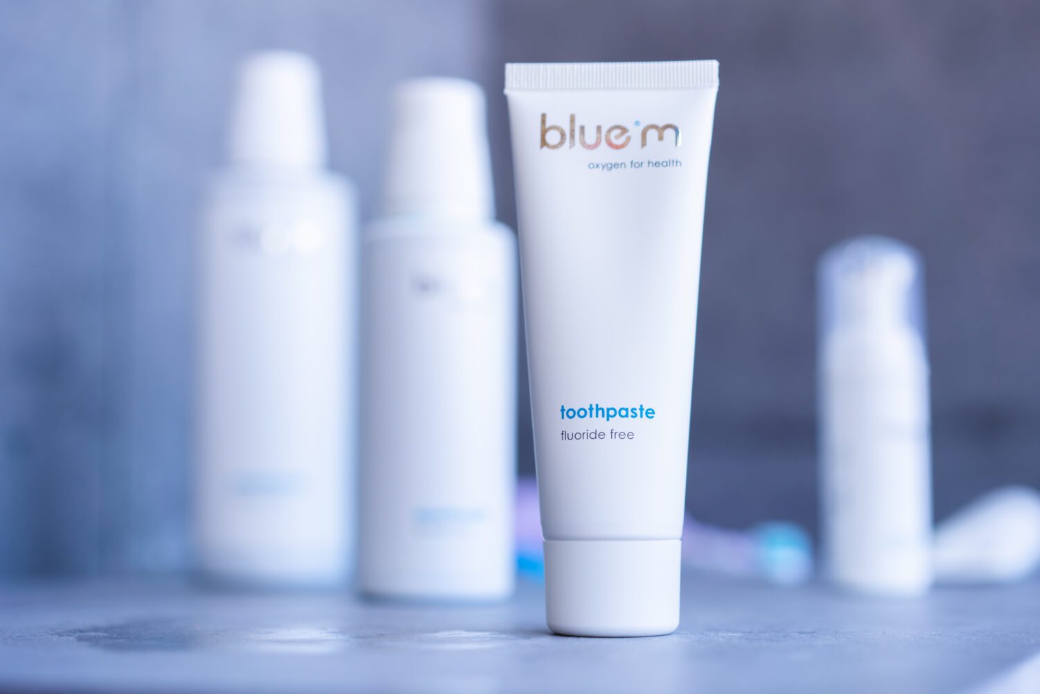 bluem® toothpaste tube with bluem® products in the background