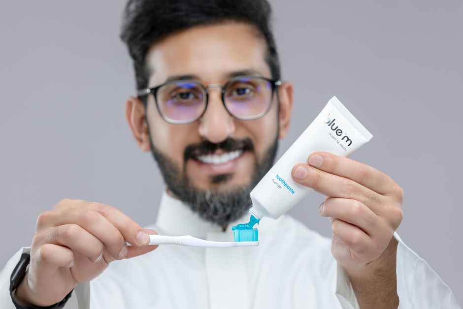 Man squeezing bluem® toothpaste onto a soft toothbrush