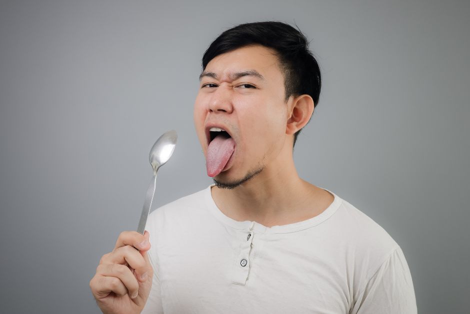 Man holding spoon to his tongue