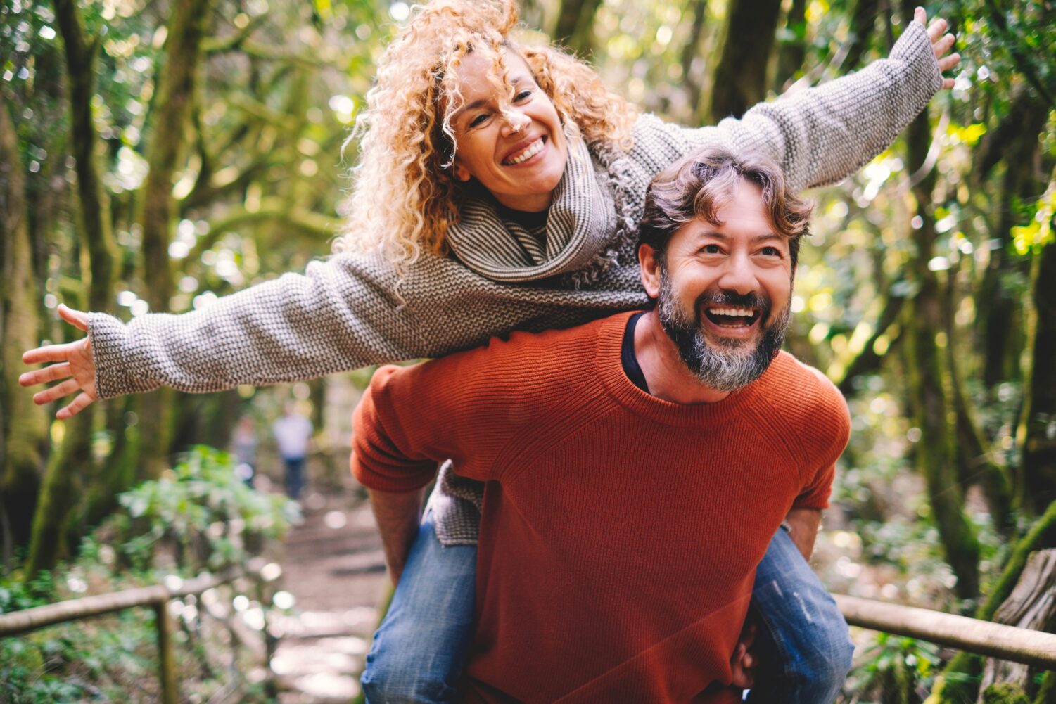 Middle aged woman on a mans back in a wooded area